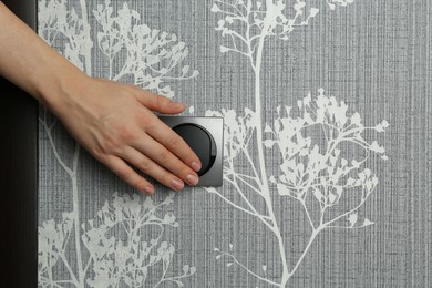 Photo of Woman turning light switch on, closeup view