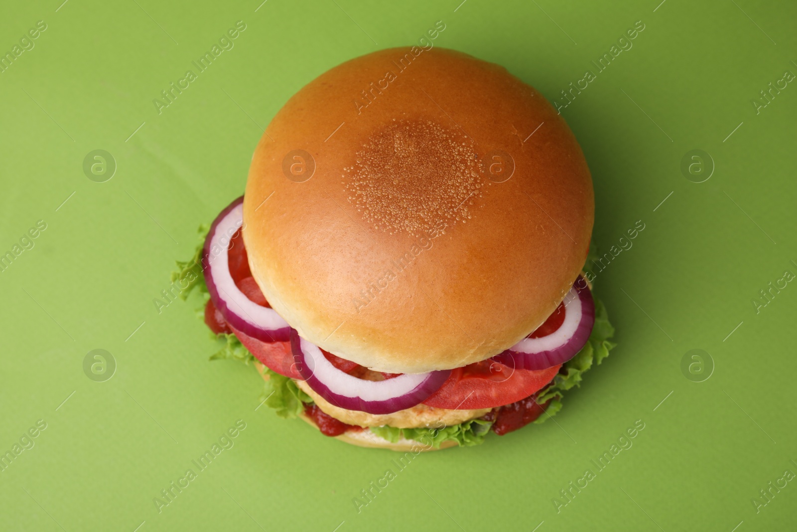 Photo of Delicious vegan burger with chickpea cutlet on green background, top view