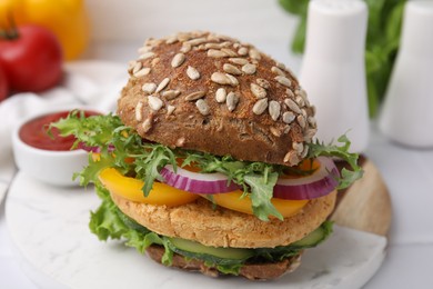 Photo of Delicious vegan burger with chickpea cutlet on white tiled table, closeup