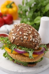 Photo of Delicious vegan burger with chickpea cutlet on white table, closeup