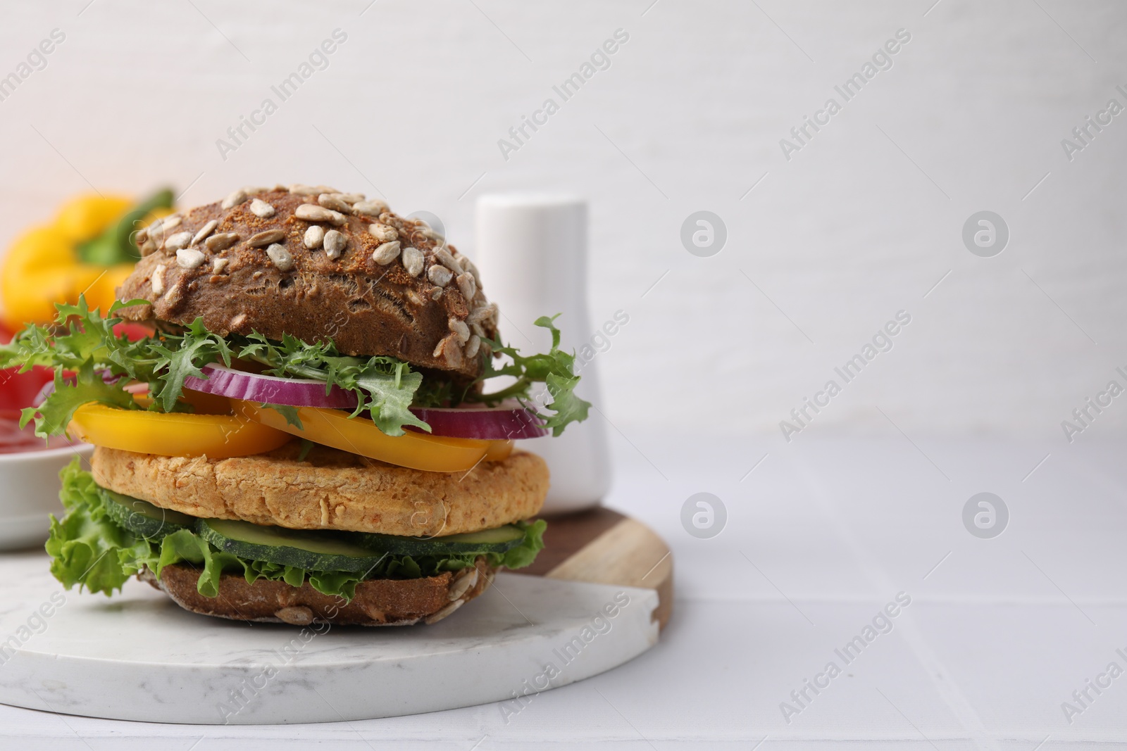 Photo of Delicious vegan burger with chickpea cutlet on white tiled table. Space for text