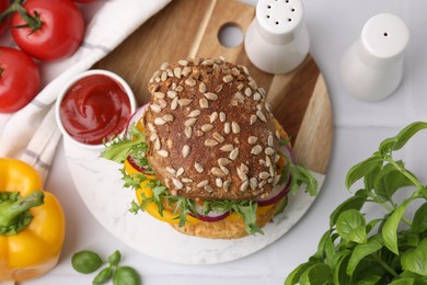 Photo of Delicious vegan burger with chickpea cutlet on white tiled table, flat lay