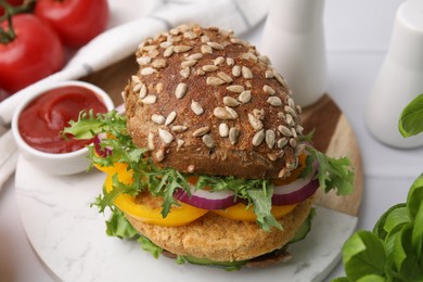 Photo of Delicious vegan burger with chickpea cutlet on white tiled table, closeup