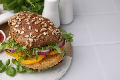 Photo of Delicious vegan burger with chickpea cutlet on white tiled table, closeup. Space for text