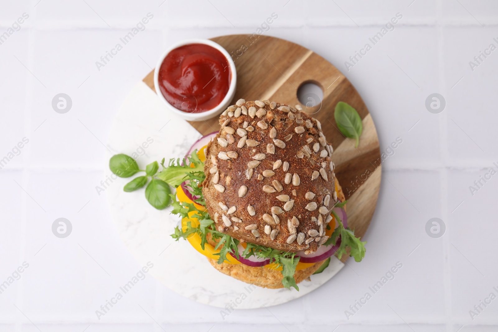 Photo of Delicious vegan burger with chickpea cutlet on white tiled table, top view