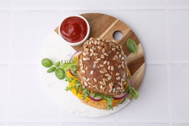 Delicious vegan burger with chickpea cutlet on white tiled table, top view