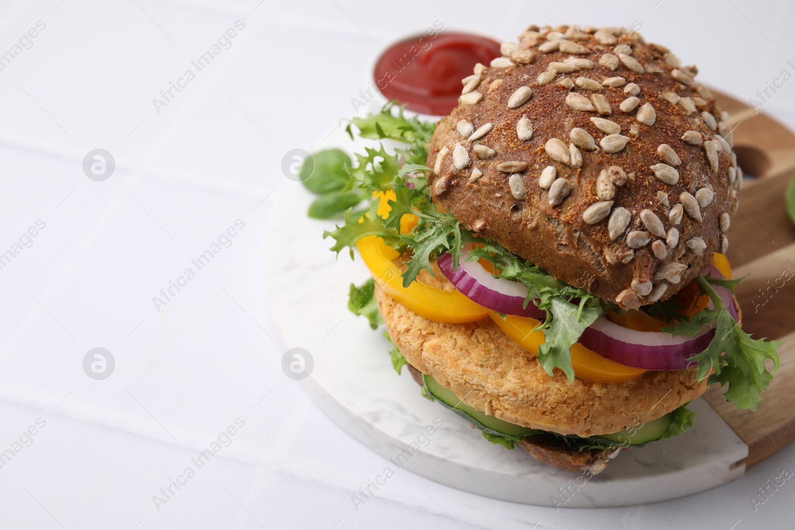 Photo of Delicious vegan burger with chickpea cutlet on white tiled table, closeup. Space for text