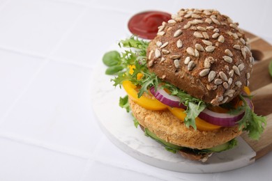 Photo of Delicious vegan burger with chickpea cutlet on white tiled table, closeup. Space for text