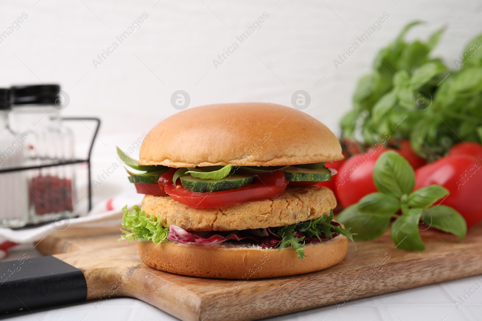 Photo of Delicious vegan burger with chickpea cutlet on white tiled table