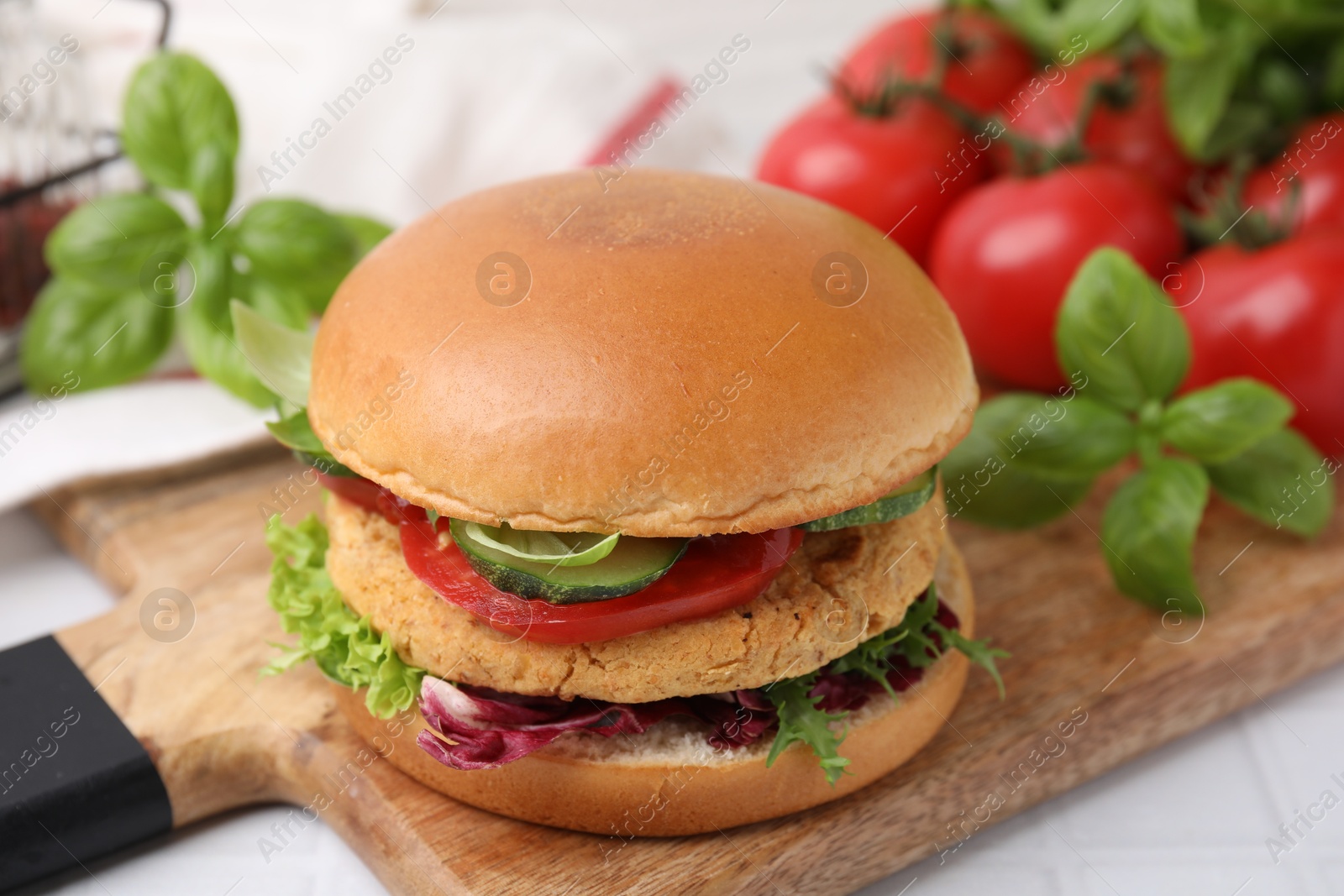 Photo of Delicious vegan burger with chickpea cutlet on white tiled table, closeup