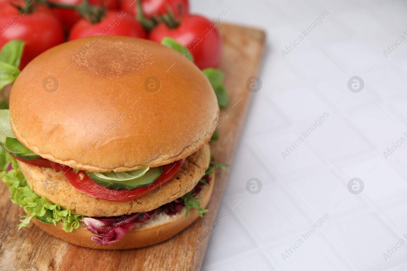 Photo of Delicious vegan burger with chickpea cutlet on white tiled table, closeup. Space for text