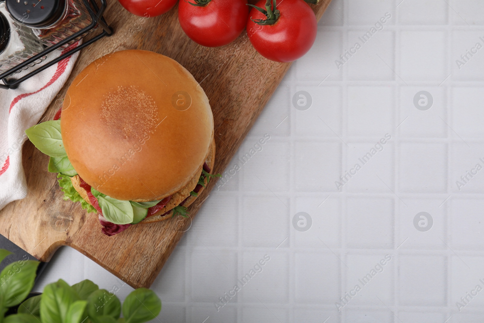 Photo of Delicious vegan burger with chickpea cutlet on white tiled table, flat lay. Space for text