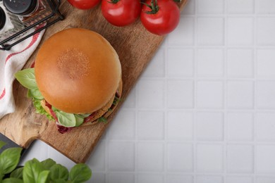 Photo of Delicious vegan burger with chickpea cutlet on white tiled table, flat lay. Space for text