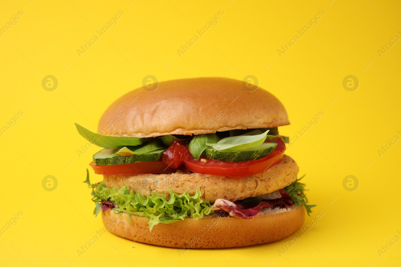 Photo of Delicious vegan burger with chickpea cutlet on yellow background, closeup