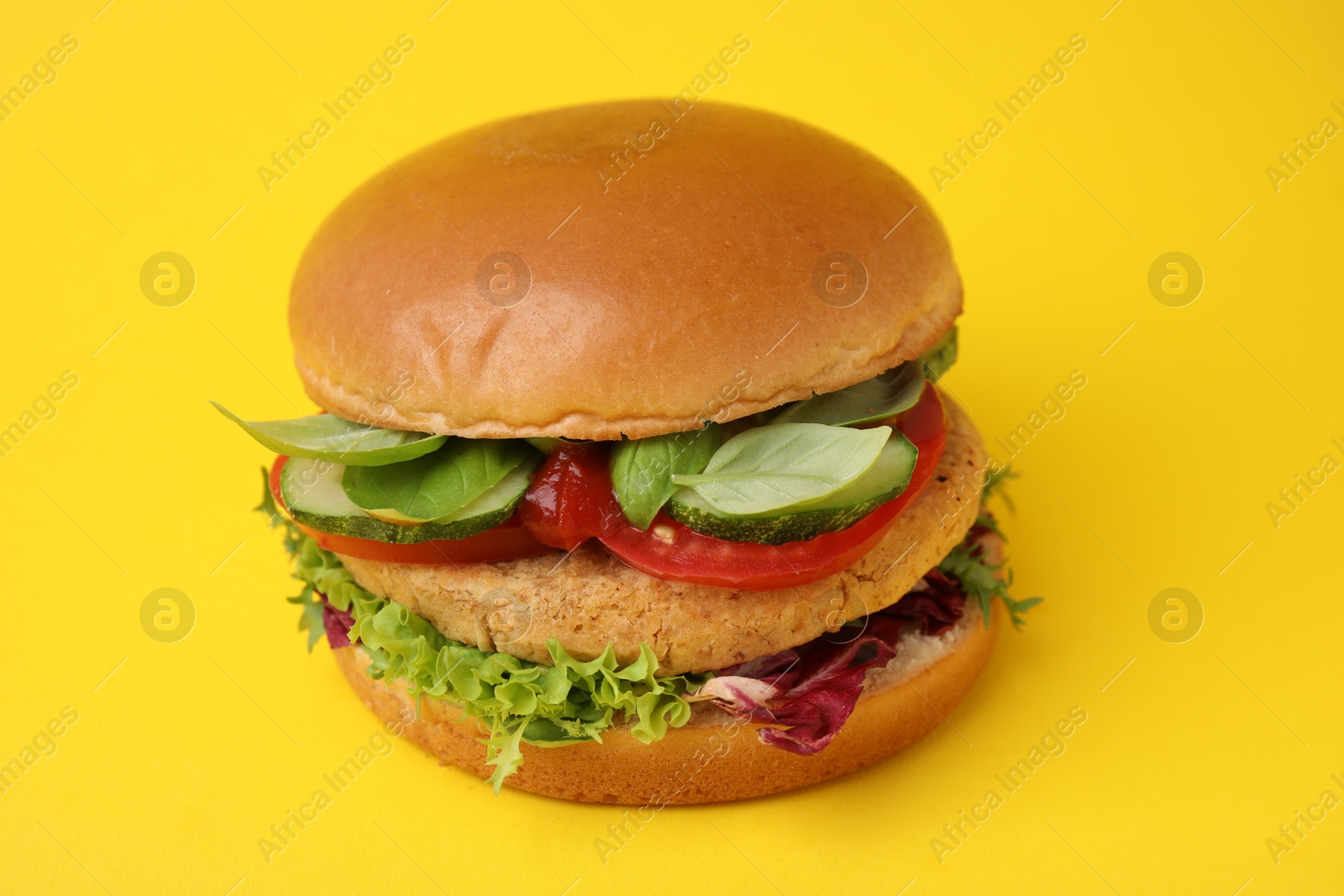 Photo of Delicious vegan burger with chickpea cutlet on yellow background, closeup