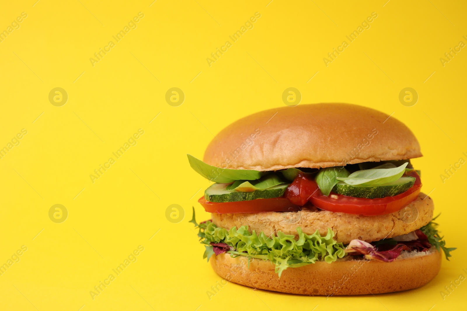 Photo of Delicious vegan burger with chickpea cutlet on yellow background. Space for text