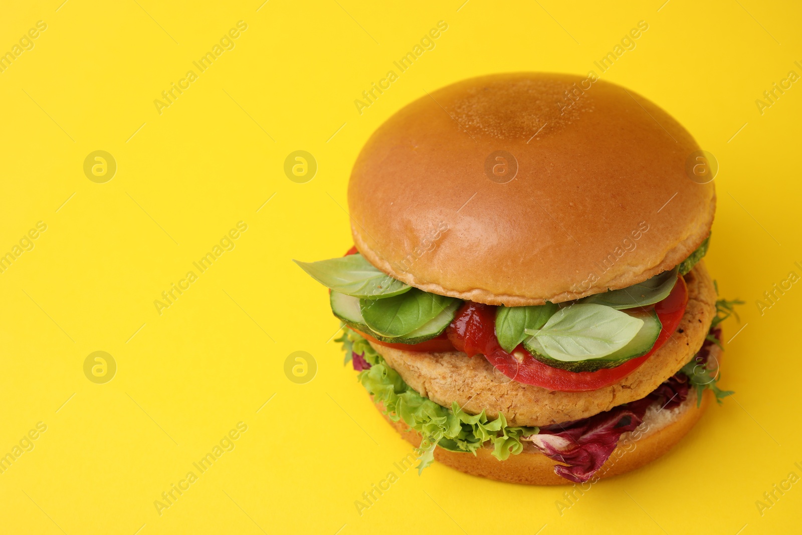 Photo of Delicious vegan burger with chickpea cutlet on yellow background. Space for text