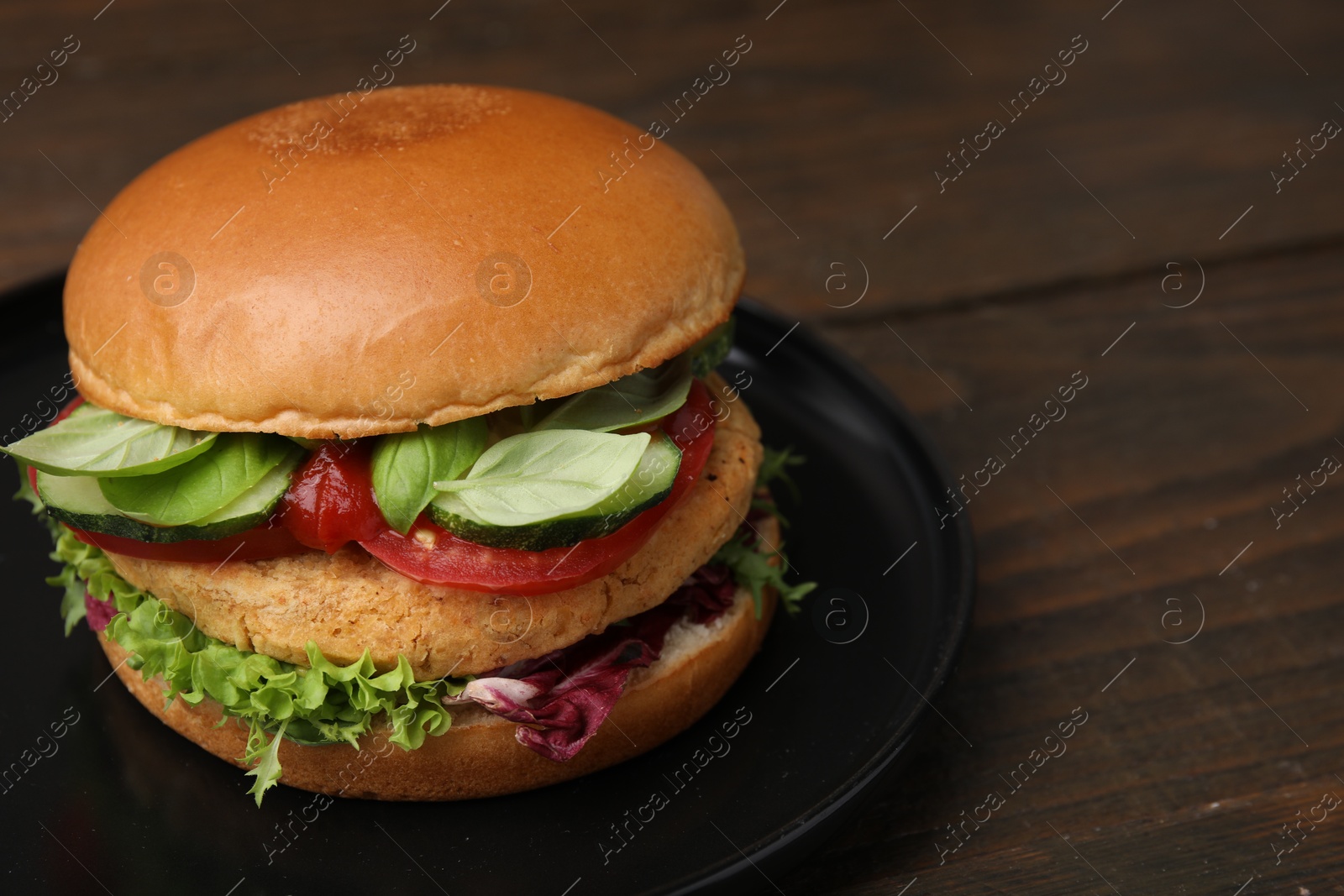 Photo of Delicious vegan burger with chickpea cutlet on wooden table, closeup. Space for text