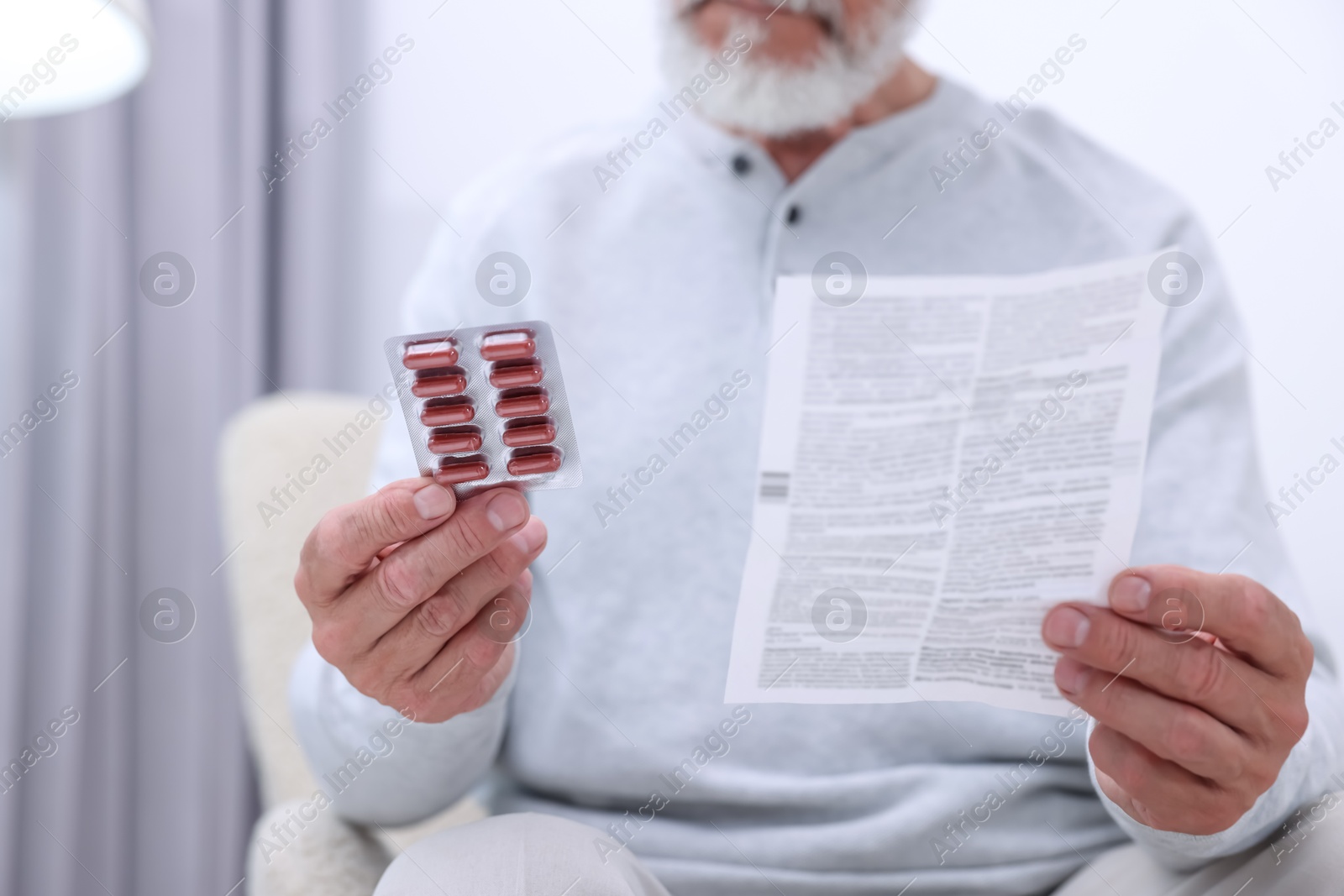 Photo of Senior man with pills and medicine instruction at home, closeup