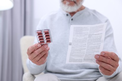 Photo of Senior man with pills and medicine instruction at home, closeup