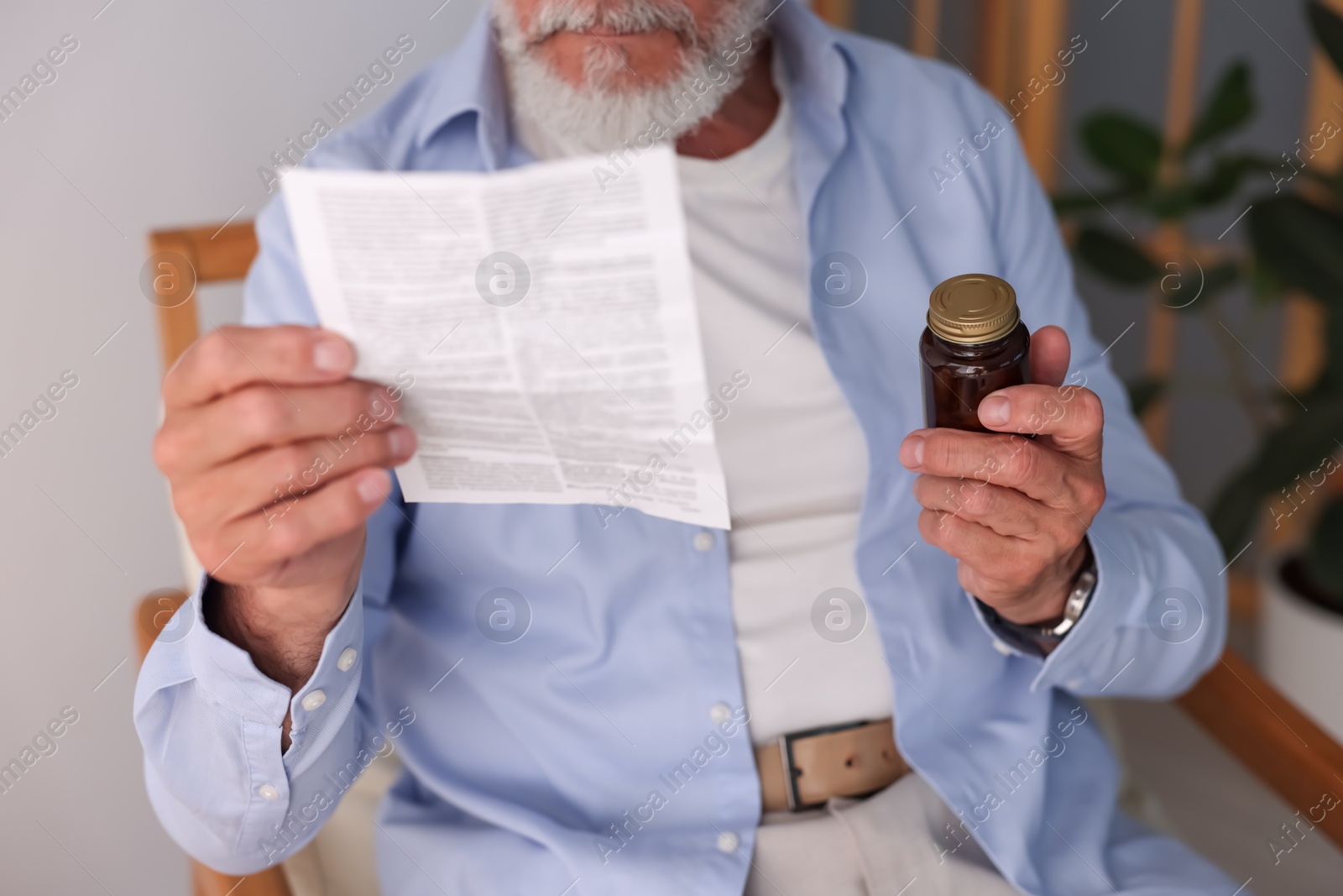 Photo of Senior man with pills reading medicine instruction at home, closeup