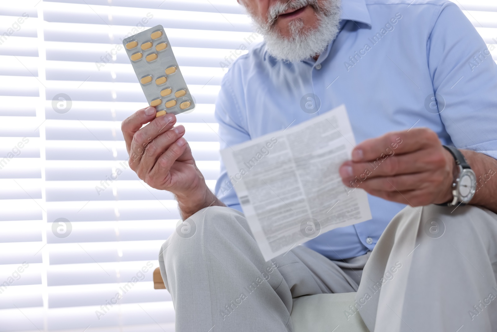 Photo of Senior man with pills reading medicine instruction at home, closeup