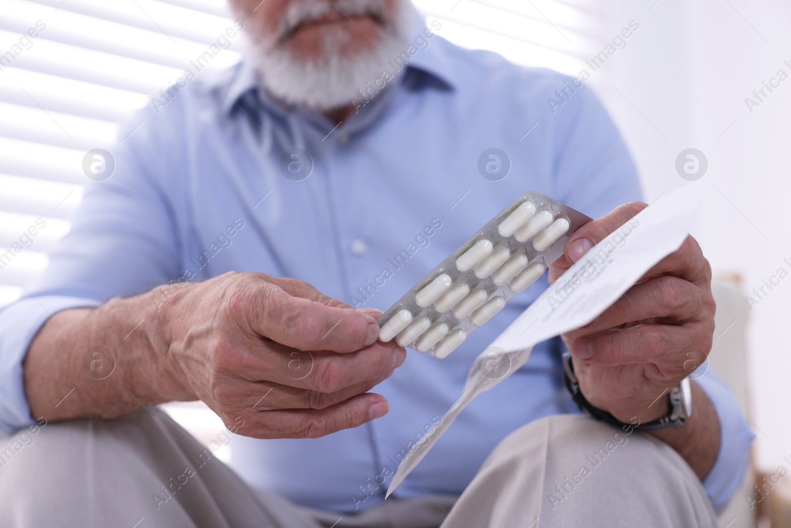 Photo of Senior man with pills and medicine instruction at home, closeup