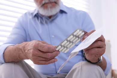 Senior man with pills and medicine instruction at home, closeup