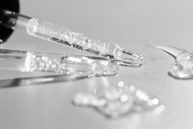 Photo of Cosmetic serum and pipettes on grey background, closeup