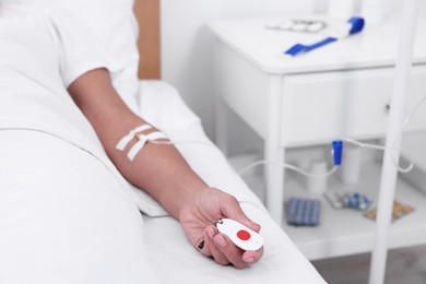 Photo of Senior woman with emergency call button on bed in hospital, closeup