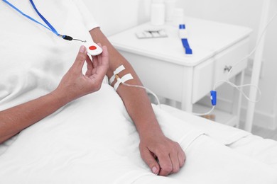 Photo of Senior woman with emergency call button on bed in hospital, closeup