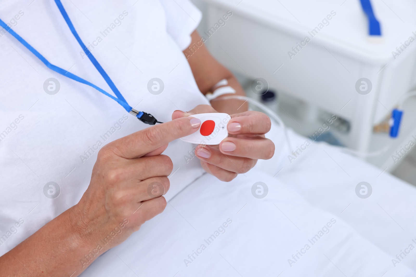 Photo of Senior woman pressing emergency call button on bed in hospital, closeup