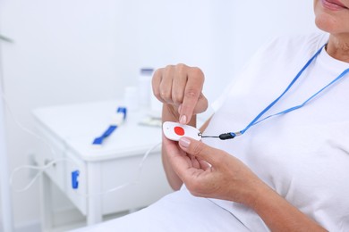 Photo of Senior woman with emergency call button on bed in hospital, closeup