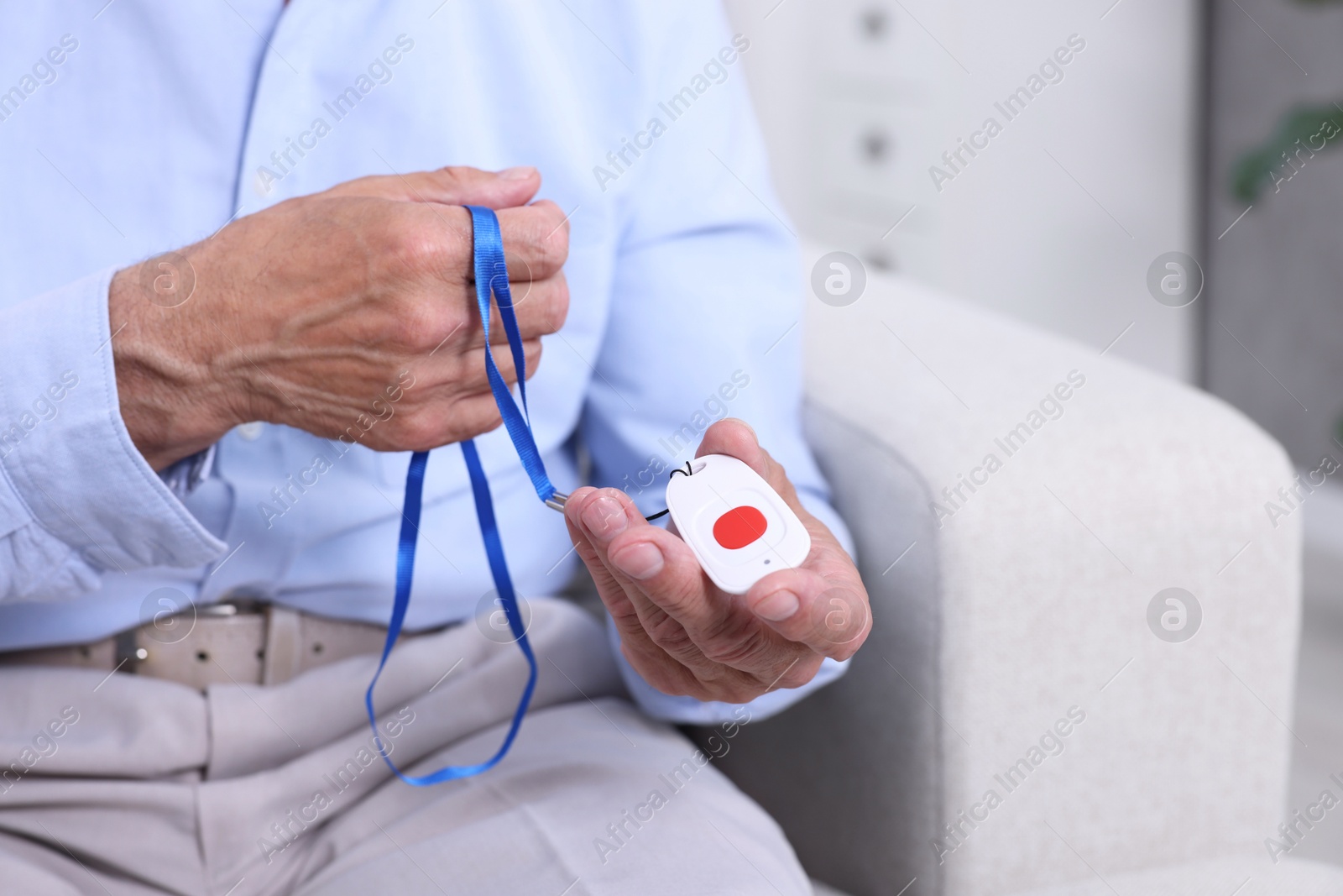 Photo of Senior man with emergency call button at home, closeup