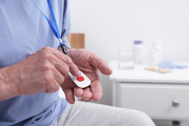 Senior man pressing emergency call button on bed in hospital, closeup