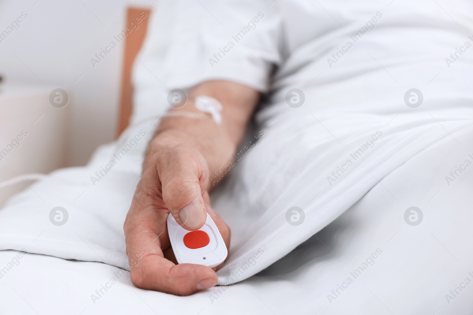 Photo of Senior man with emergency call button on bed in hospital, closeup