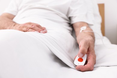 Photo of Senior man with emergency call button on bed in hospital, closeup