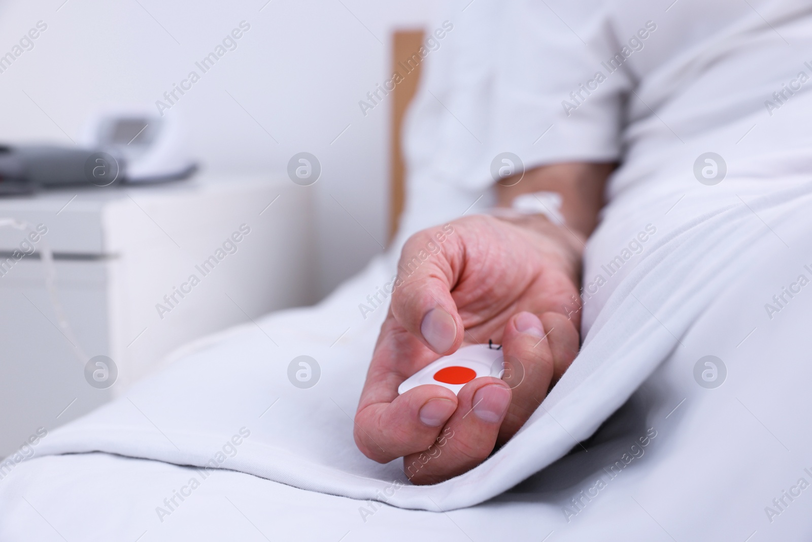 Photo of Senior man with emergency call button on bed in hospital, closeup