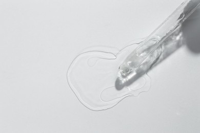 Cosmetic oil and pipette on light grey background, top view