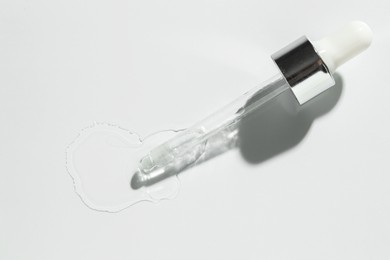 Photo of Cosmetic oil and pipette on light grey background, top view