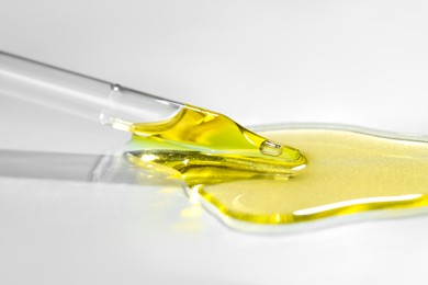 Photo of Cosmetic oil and pipette on light grey background, closeup