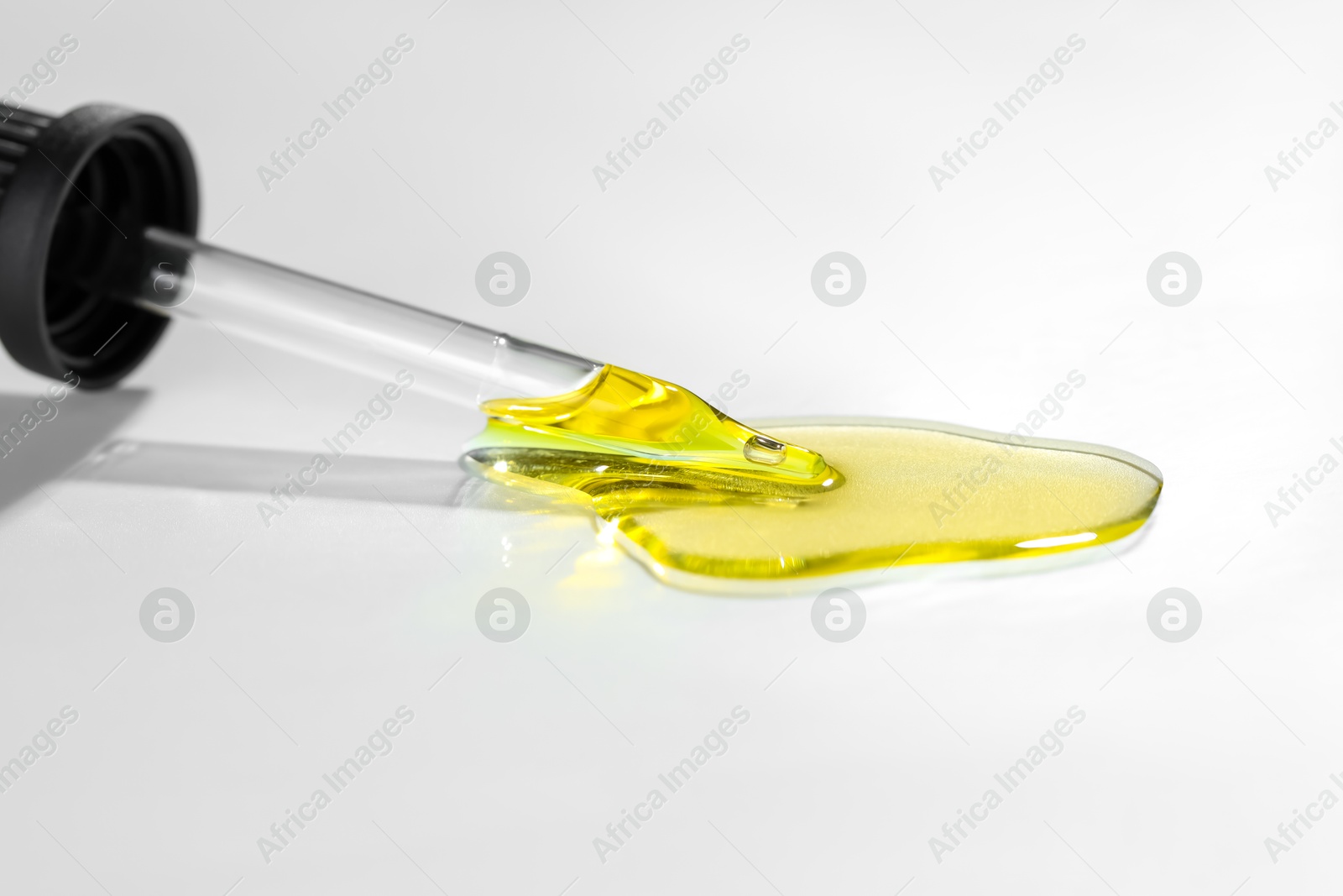 Photo of Cosmetic oil and pipette on light grey background, closeup