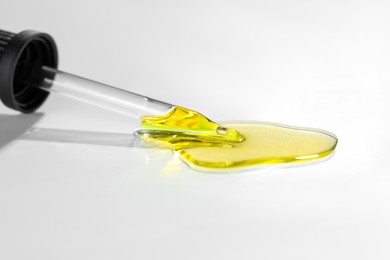 Photo of Cosmetic oil and pipette on light grey background, closeup