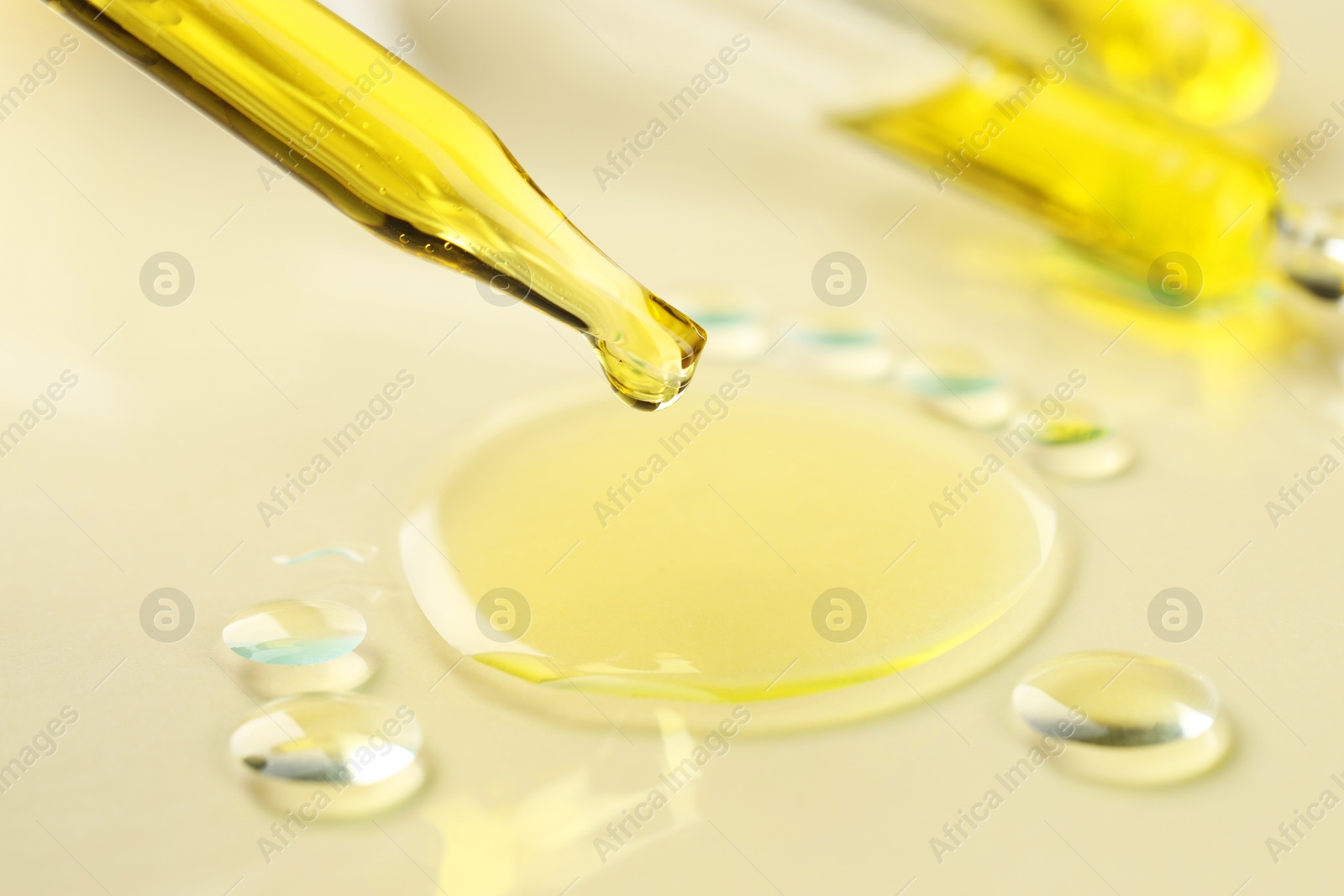 Photo of Cosmetic oil dripping from pipette on dark beige background, closeup