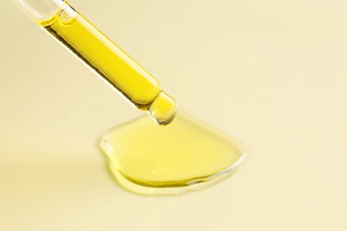 Photo of Cosmetic oil dripping from pipette on dark beige background, closeup. Space for text