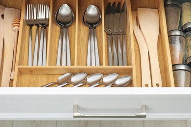 Photo of Box with cutlery in drawer, closeup. Kitchen utensils storage