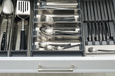 Photo of Box with cutlery in drawer, closeup. Kitchen utensils storage