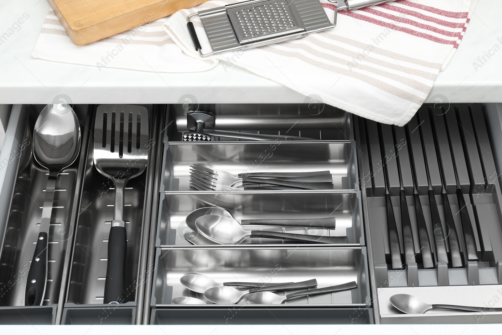 Photo of Box with cutlery in drawer, closeup. Kitchen utensils storage