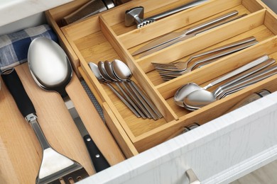 Photo of Box with cutlery in drawer, closeup. Kitchen utensils storage