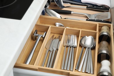 Photo of Box with cutlery in drawer, closeup. Kitchen utensils storage